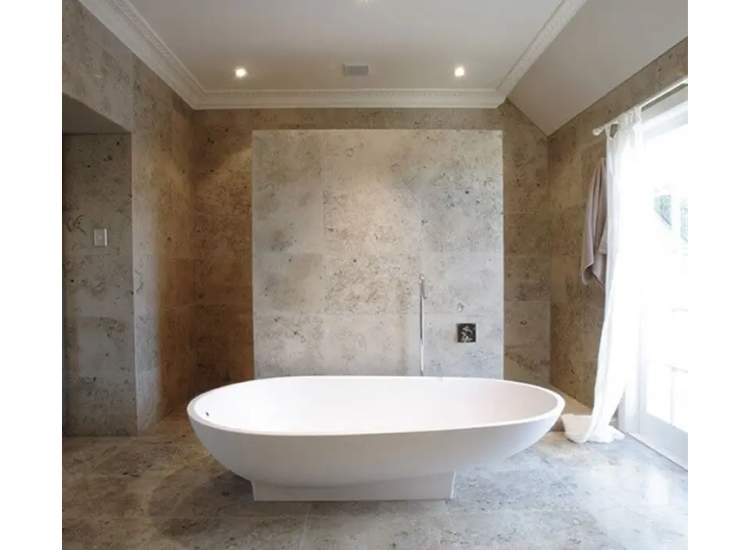 A spacious bathroom designed with natural limestone tiles offering a timeless and classic look to the bathroom