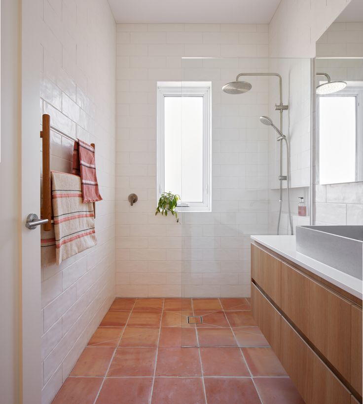 A bathroom with terracotta tile flooring with orange and earthy color, giving vintage vibes and a dramatic look
