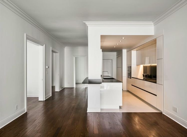 An empty kitchen interior featuring white walls and a modern, sleek countertop, illuminated to highlight the clean and contemporary design.