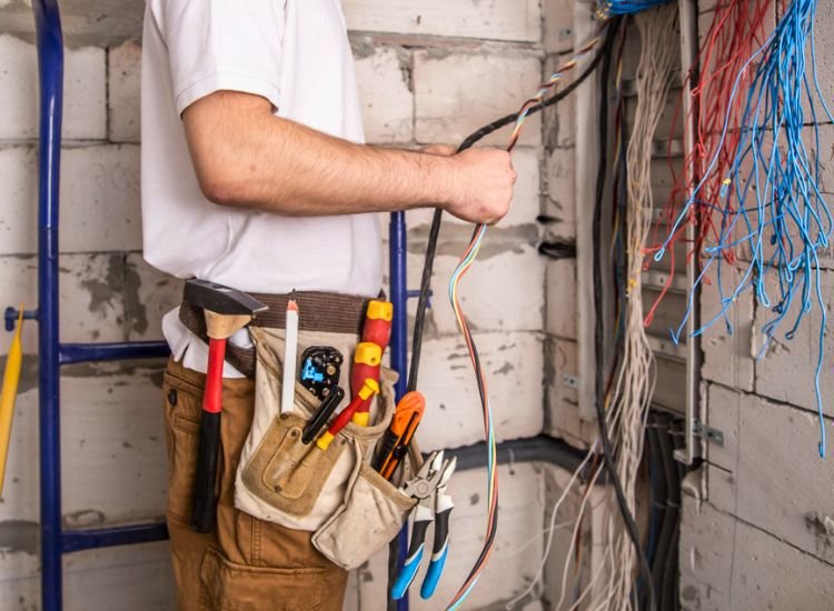 A professional electrical wireman working on home wiring, using essential tools to ensure proper installation and functionality of the electrical system.