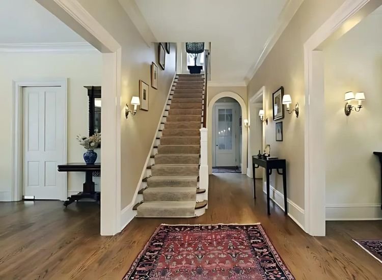 A straight staircase in a modern living room, featuring wooden steps with natural light illuminating the space.