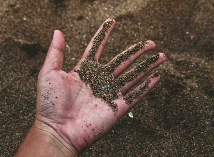 A person's hand inspecting soil quality and testing it to ensure suitability for home construction, evaluating land conditions for building.