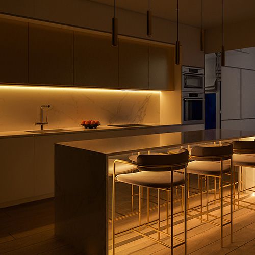 A contemporary kitchen with a vibrant, energetic illumination originating from an under-the-counter light source