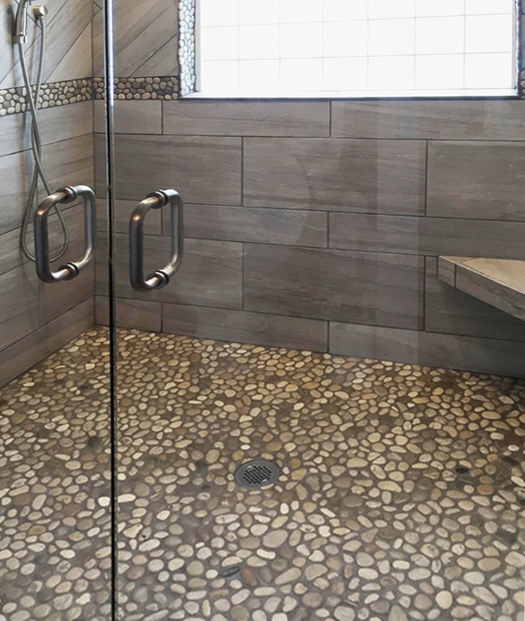 A stylish small bathroom showcasing a pebble tile floor, combining sophistication and earthy aesthetics