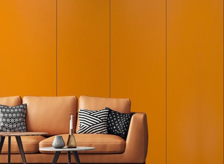 An orange leather sofa in front of a wall with a wooden table. Unicore laminates add a touch of elegance