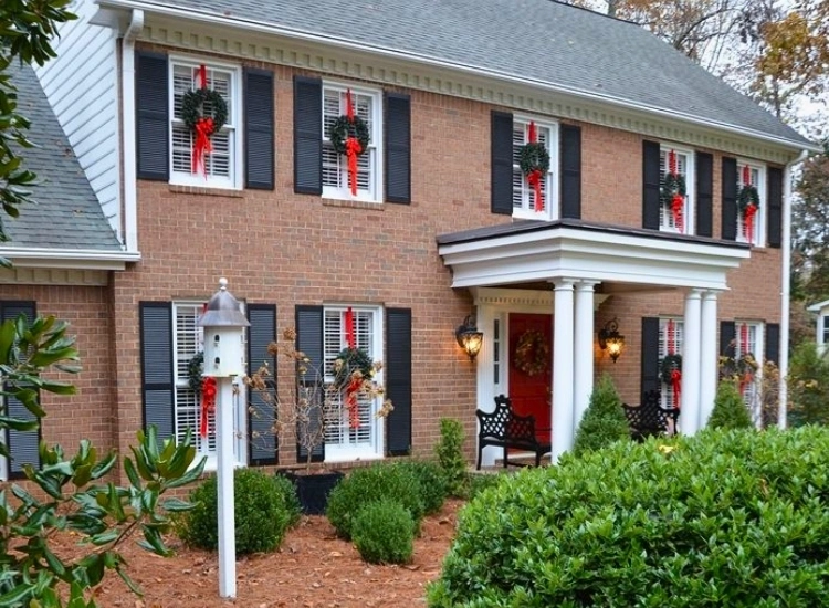 "Christmas wreaths hanging on exterior windows, enhancing the holiday charm. Christmas tree picture included."