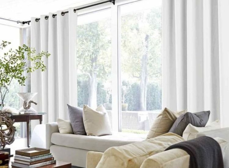 Beautiful living room bathed in natural daylight, with bright light flooding the space, complemented by white curtains and a white sofa.