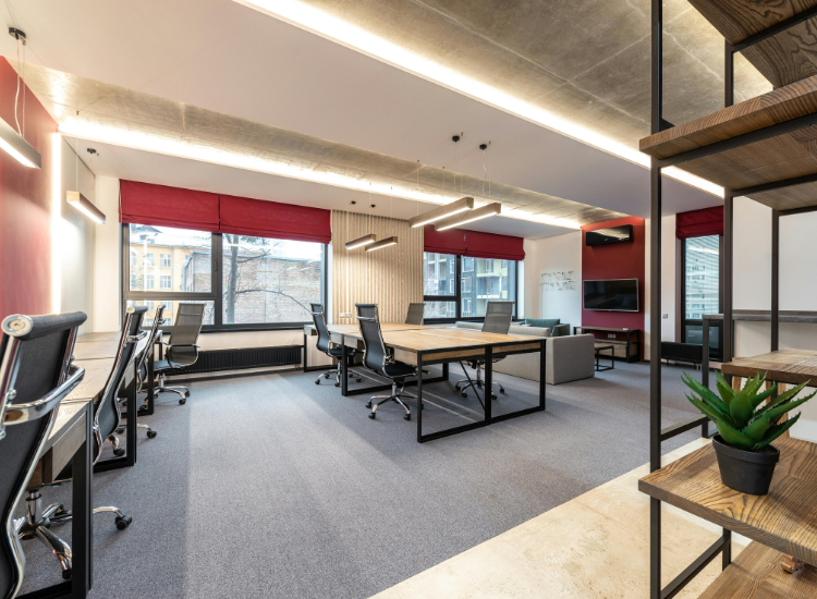 Balanced office workspace with perfect lighting, overhead fixtures, and a spacious layout, featuring red window curtains that create a strong focal point.