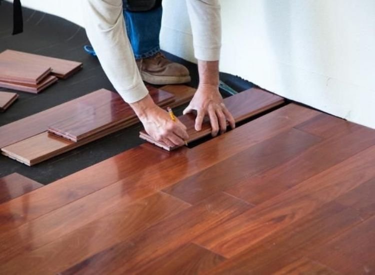 A man installing wood flooring in a room, carefully laying down each plank to create a beautiful and durable surface